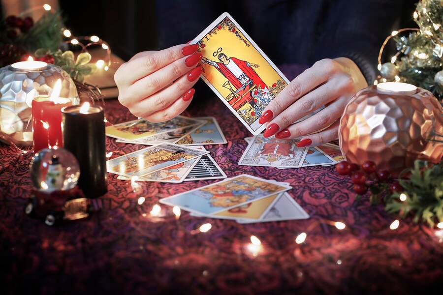 Slika tarot kart ob mladi luni v kozorogu, simbolizirajoči prehod v leto 2025 s tedenskim vpogledom za znamenja zodiaka.
