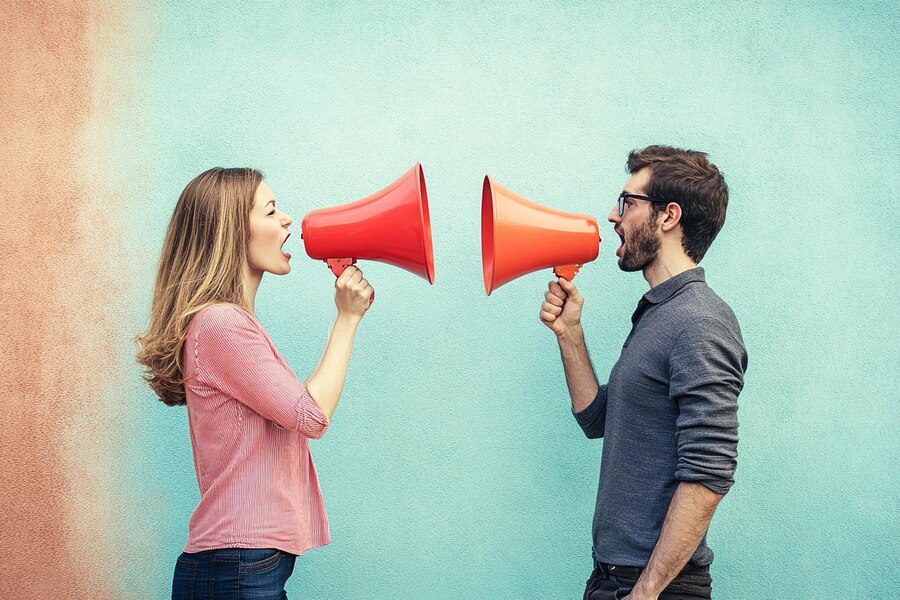 Par, ki se pogovarja, z vidno osredotočenostjo na intonacijo in ton glasu, kar odraža pomembnost komunikacije v ljubezenskih odnosih.